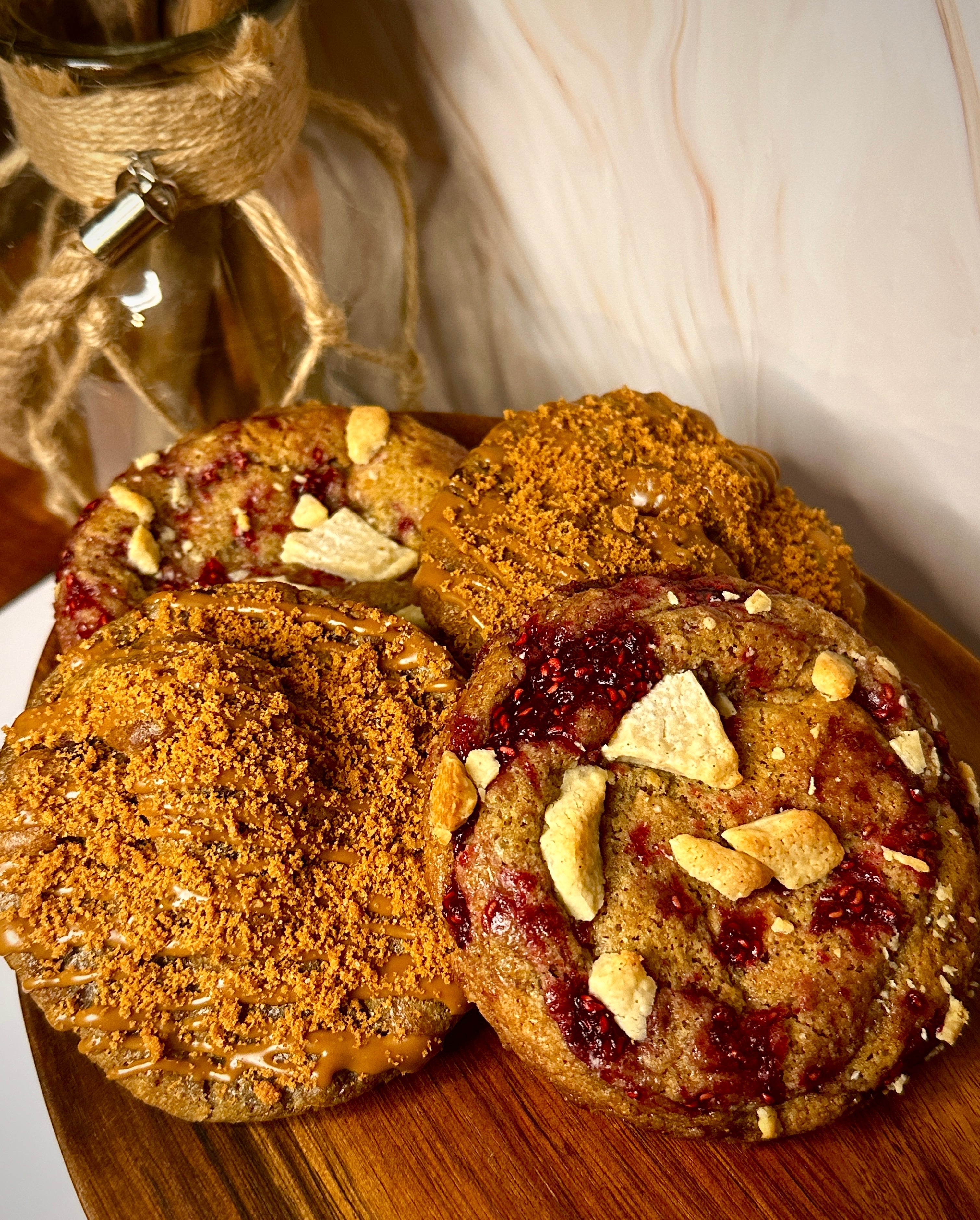 Artisanal cookies featuring drizzled biscoff and white chocolate and raspberry jam.